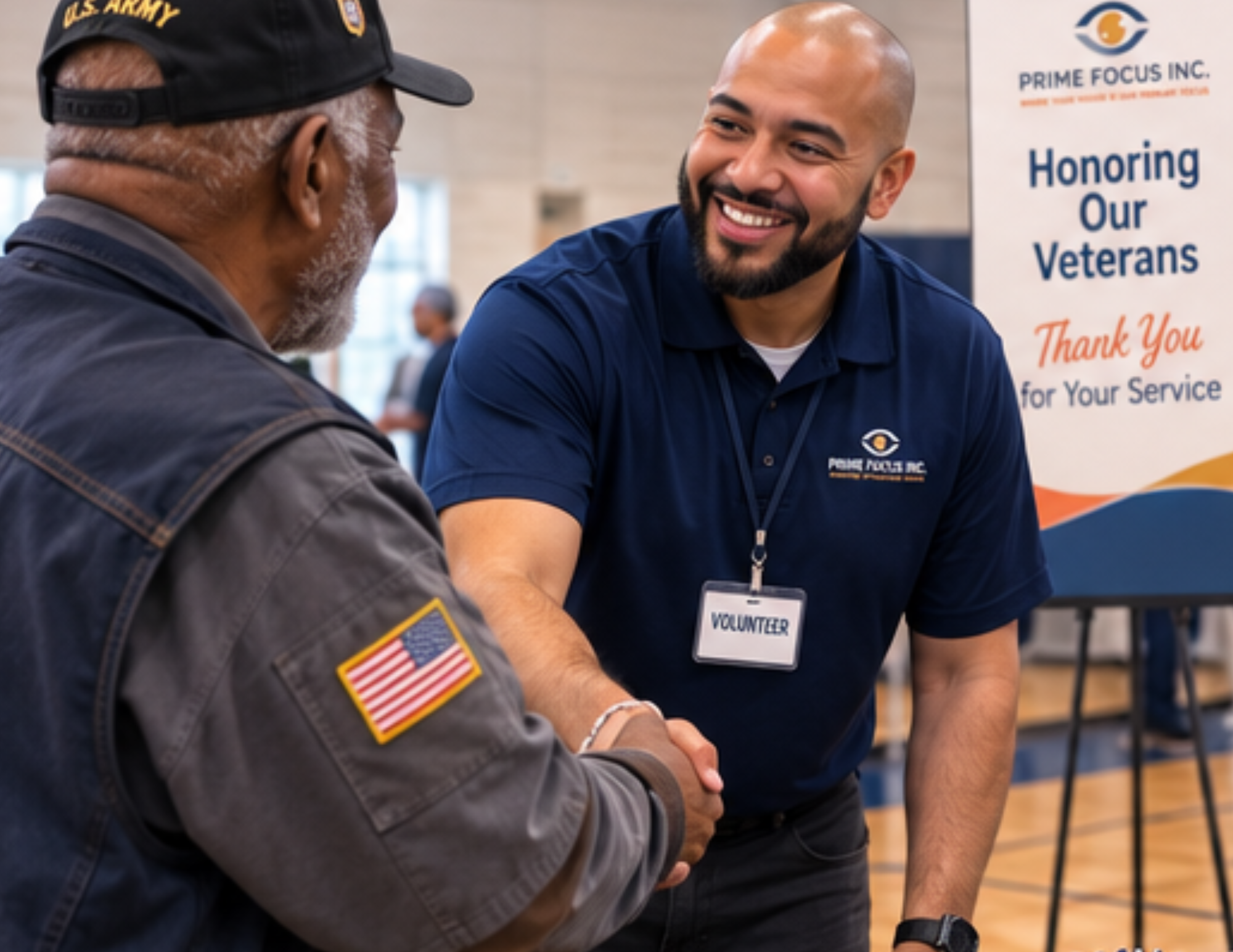 A Prime Focus staff member warmly shakes hands with a veteran participant beneath an "Honoring Our Veterans" banner at a Community Vision Day.